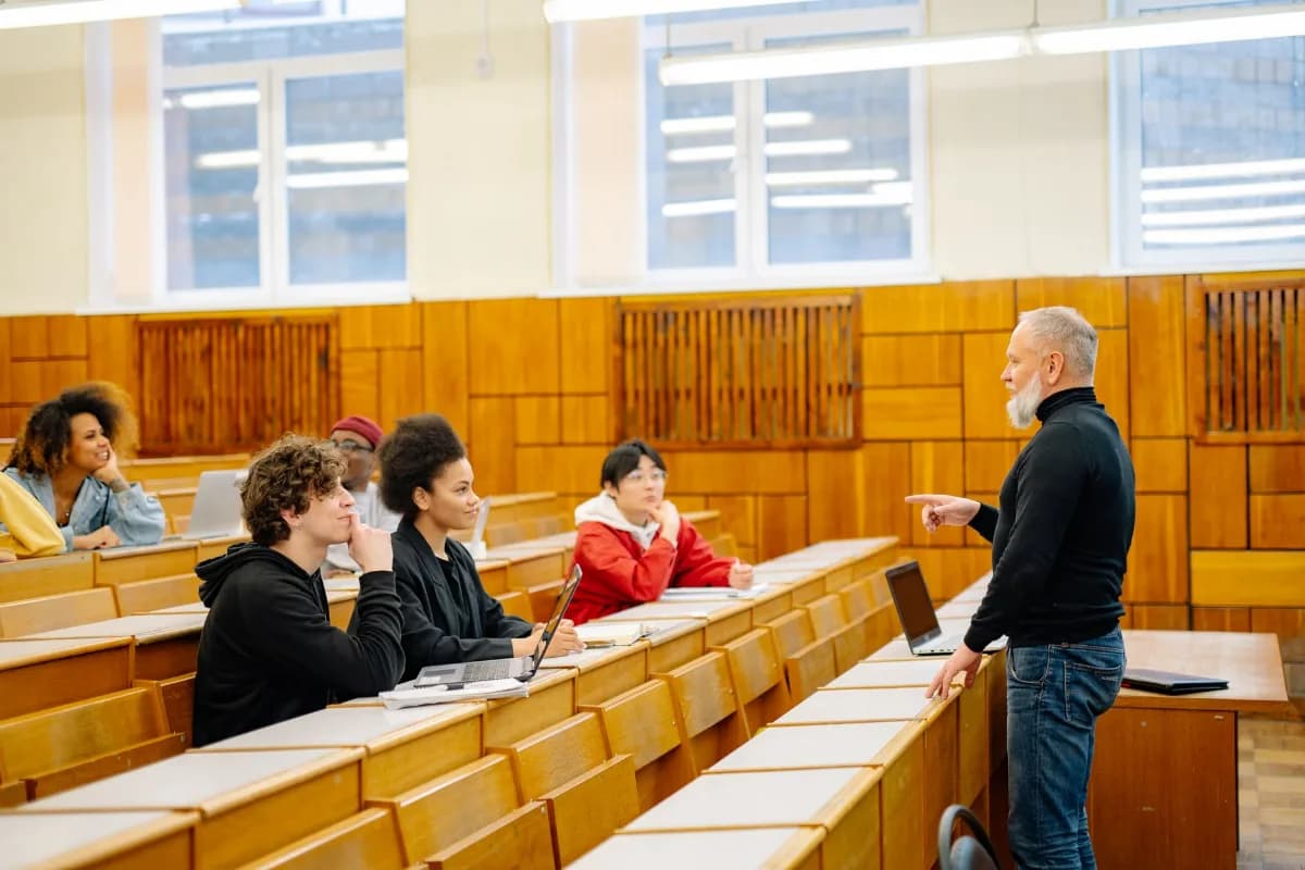 Professor conversando com estudantes adultos em uma sala de aula universitária