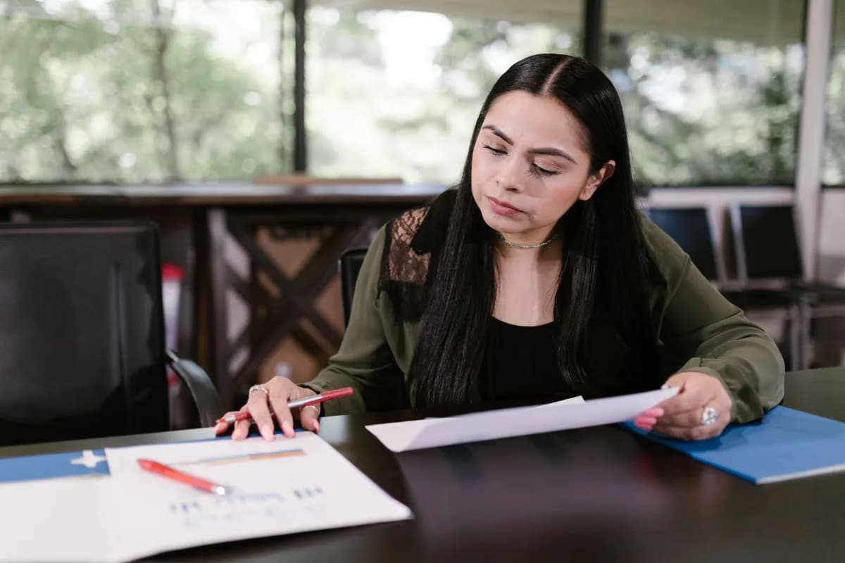 Profissional em um escritório lendo documentos com atenção sobre a mesa de trabalho
